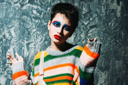 Female beauty, fashion. Attractive female model posing in stylish bright clothes over gray background. Stylish clothes and creative makeup. Studio shot.の写真素材