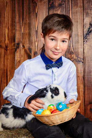 Easter holidays. Happy child boy sitting on a haystack with Easter Bunny.の写真素材