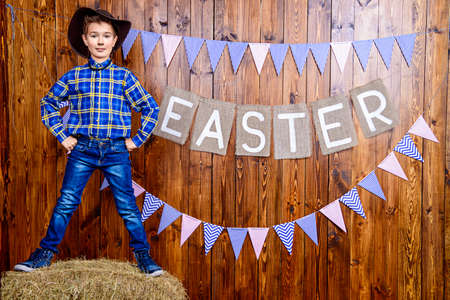 Portrait of a cute nine year old boy posing in Easter decorations. Western style, cowboy. Kid's fashion. Easter.の写真素材