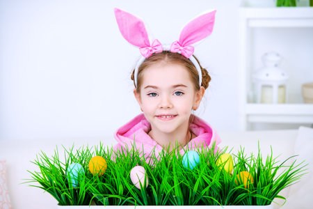 Easter holidays. Funny happy little girl wearing bunny ears celebrating Easter at home.