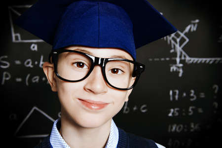 Funny smart boy in formal suit and glasses over school blackboard. Educational concept. の写真素材