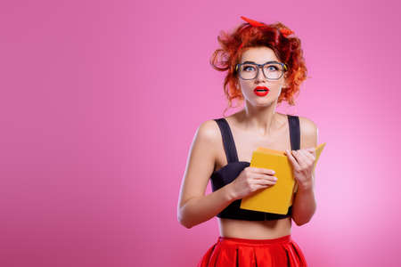 Smart pretty girl wearing in glasses with book in her hands. Pin-up retro style.の写真素材