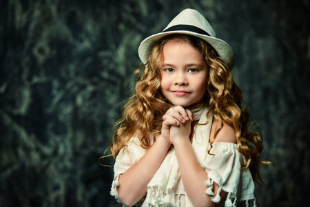 Portrait of a cute little girl with beautiful curly hair. Kid's fashion, style.