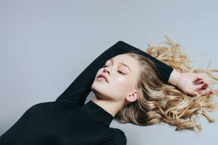 Portrait of an attractive lying girl with blonde wavy hair. Beauty, fashion concept. Cosmetics and make-up.の写真素材