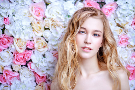 Beautiful sensual woman posing on a background of roses. Inspiration of spring and summer. Perfume, cosmetics concept.の写真素材