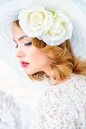 Close-up portrait of a charming bride in lace dress and elegant broad-brimmed hat. Wedding. Make-up and hairstyle. Beauty, fashion.の写真素材