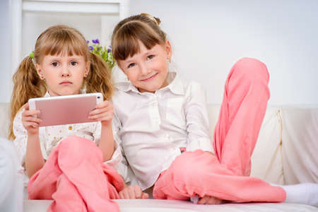 Modern family concept. Two girls sisters are playing a tablet pc. Problems of the modern generation.の写真素材