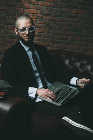 Young brutal businessman in suit working on a laptop. Business concept. Modern technologies.