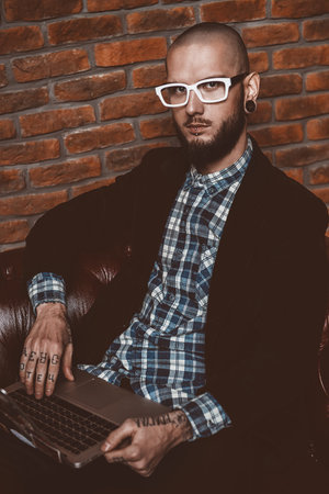 Young brutal businessman is working at home using his laptop. Male beauty, fashion. Business...