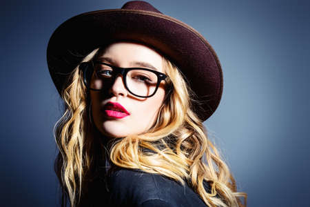 Attractive fashionable young woman wearing in hat and glasses. Optics style. Studio shot.の写真素材