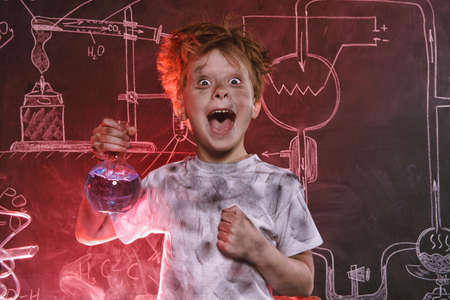 Funny schoolboy doing experiments in the laboratory. Explosion in the laboratory. Science and education.の写真素材