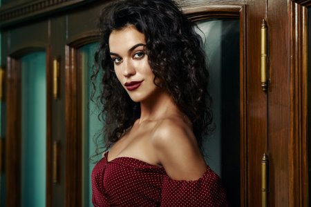 Charming young woman dressed in elegant burgundy dress on a city street. Beauty, fashion concept....