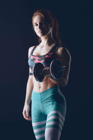 Muscular young woman with beautiful athletic body doing exercises with dumbbells. Fitness, bodybuilding. Health care.の写真素材