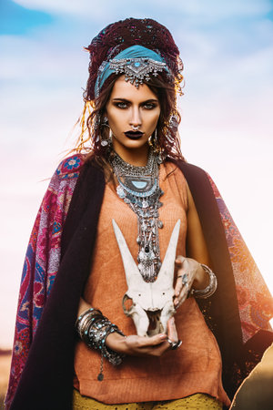 Magnificent gypsy fortune teller with a skull in the rays of the sunset. 