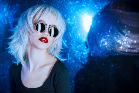 Close-up portrait of a beautiful blonde woman in stylish sunglasses over dark background. Beauty, fashion concept. Make-up and cosmetics. Studio shot.の写真素材