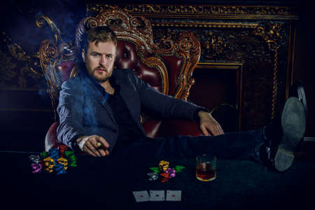 Rich gambler man with the cards and chips in casino. Gambling, playing cards and roulette.の写真素材