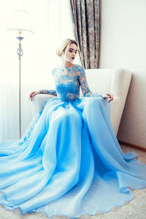 Full length portrait of a magnificent young woman in elegant long blue dress. Luxurious apartments.  Wedding fashion.の写真素材