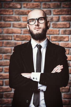 Portrait of a businessman in elegant classic suit and piercing in the ears and lips. Men's beauty, fashion.の写真素材