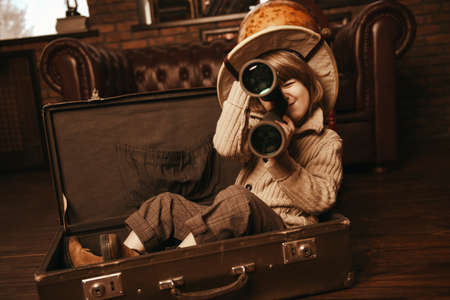 Cute child boy in a travel suitcase playing at home. Childhood. Fantasy, imagination. の写真素材