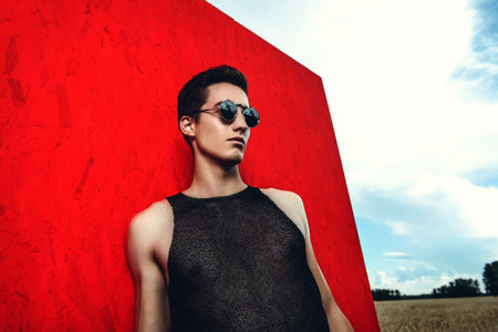 Professional handsome male model posing in a wheat field over red background. Fashion shot.