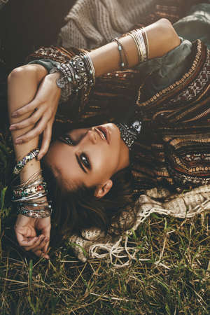 Beautiful hippie girl lying in a grass. Modern boho style. Beauty, fashion, の写真素材