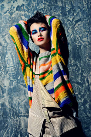 Female beauty, fashion. Attractive female model posing in stylish bright clothes over gray background. Stylish clothes and creative makeup. Studio shot.の写真素材