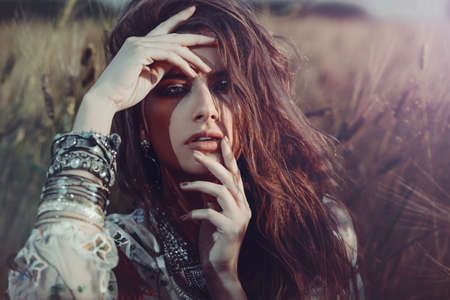 Fashion female model posing in a field. Contemporary bohemian style.の写真素材