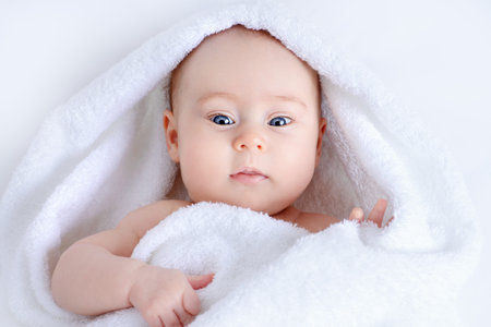 Sweet baby in a white towel after bath. Healthcare, pediatrics.