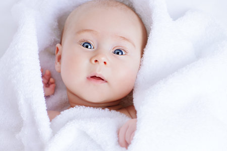 Sweet baby in a white towel after bath. Healthcare, pediatrics.