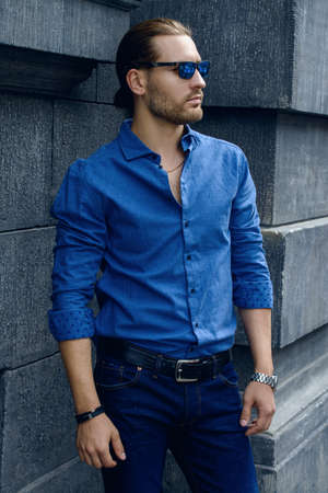 Handsome young man in jeans clothes stands on a city street. Men's fashion.の写真素材