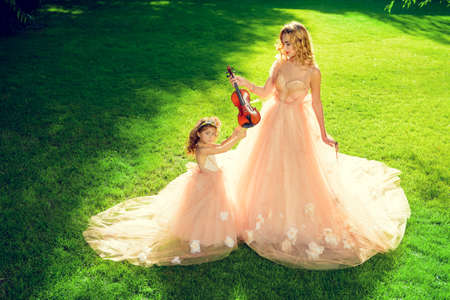 Classical music. Beautiful fairy girl teaches to play the violin a little girl. Musical fairy tales.の写真素材