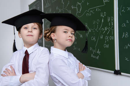 Two smart students stand at the chalkboard on a chemistry lesson. Educational concept.の写真素材