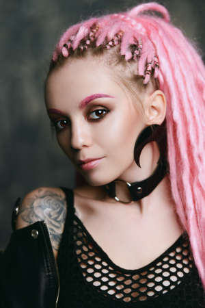 Stunning female model with pink dreadlocks posing on a dark background. Trendy hairstyles. Beauty, fashion. の写真素材