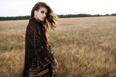 Fashion female model posing in a field. Contemporary bohemian style.