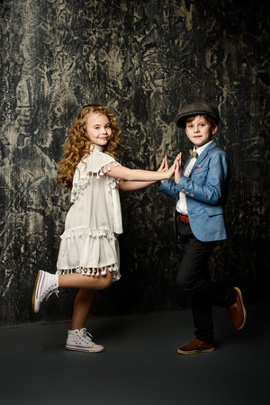 Happy child boy and girl are posing together at studio in elegant clothes. Kid's fashion, style. の写真素材