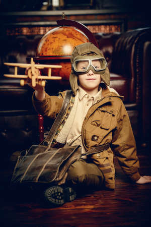 Cute dreamer boy playing with toy airplane at home. Childhood. Fantasy, imagination. の写真素材