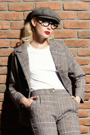 Portrait of a sexual young woman wearing checkered suit, cap and glasses. Beautiful smart girl. Beauty, fashion.の写真素材