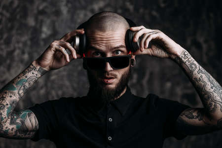 Brutal bearded man wearing sunglasses listenig to music in headphones and smiling.の写真素材