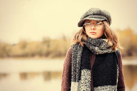 Cute teen girl in modern clothes posing outdoor. Warm autumn day. Seasonal autumn and winter fashion.の写真素材