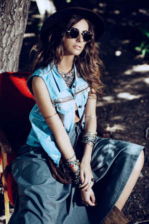 Denim style. Sexual young woman posing in jeans clothes on a street. Beauty, fashionable look. Boho style clothes and accessories.の写真素材