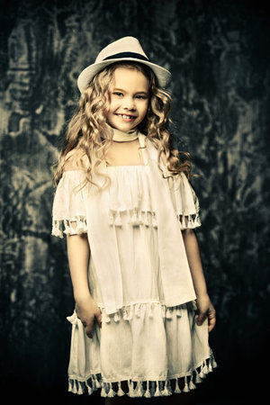 Portrait of a cute little girl with beautiful curly hair. Kid's fashion, style.