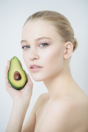 Beautiful young woman with avocado. Beauty, natural cosmetics concept. Spa, body care.