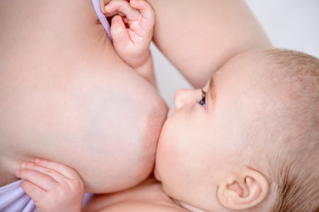 Close-up portrait of a newborn baby sucking a mother's breast. Natural feeding for babies. Baby...