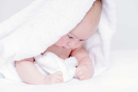 Sweet baby under a white towel after bath. Healthcare, pediatrics.の写真素材