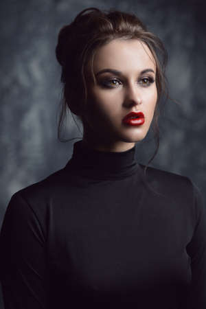 Fashion and make-up concept. Close-up portrait of an attractive young woman with bright makeup over dark background.の写真素材