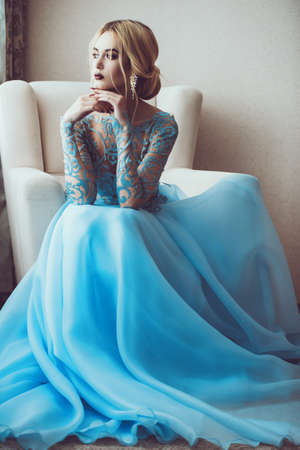Full length portrait of a magnificent young woman in elegant long blue dress. Luxurious apartments.  Wedding fashion.の写真素材