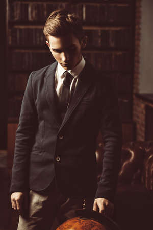 Intelligent student boy in elegant clothes standing in the library. Fashion. Educational concept.の写真素材