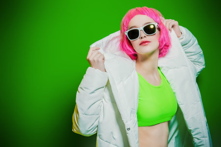 Trendy girl with pink hair wearing bright stylish clothes. Green background. Beauty, fashion, youth...