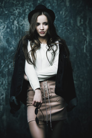 Portrait of a attractive young woman in modern youth clothes. Studio shot over dark background....