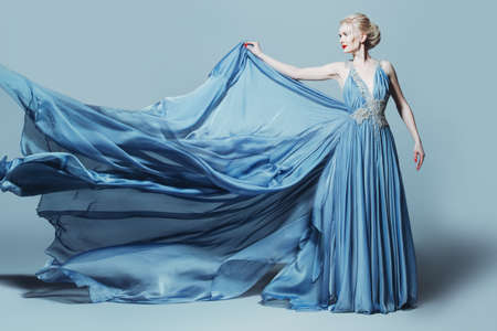 Full length portrait of a magnificent young woman in elegant long blue dress with lush skirt. の写真素材